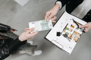 Euro banknotes, house keys and a floor plan representing the costs of buying property in Portugal